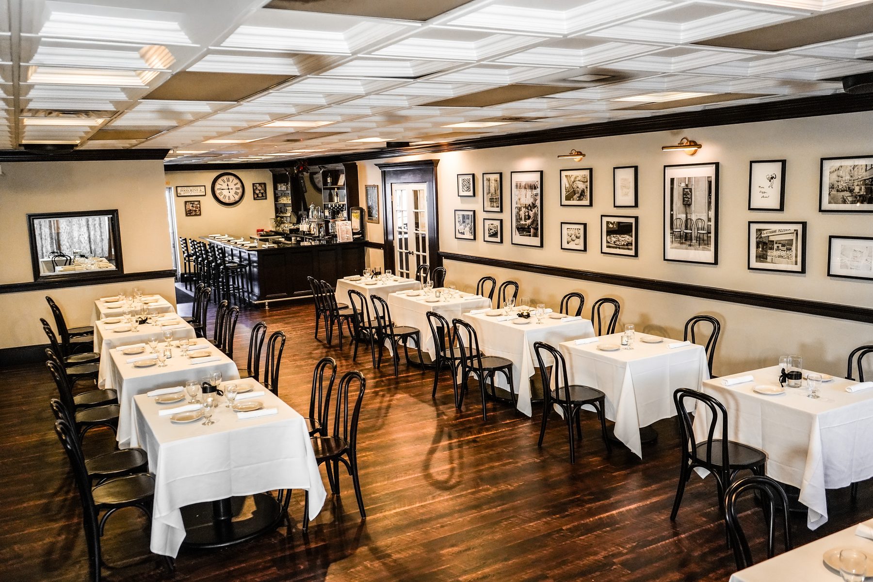 The dining room set with white tablecloths, the bar at the back